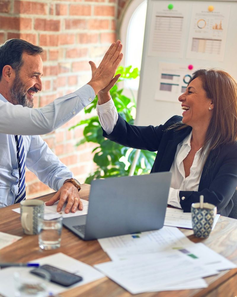 Two smiling We Are Next Target team members sharing a high five at a meeting table